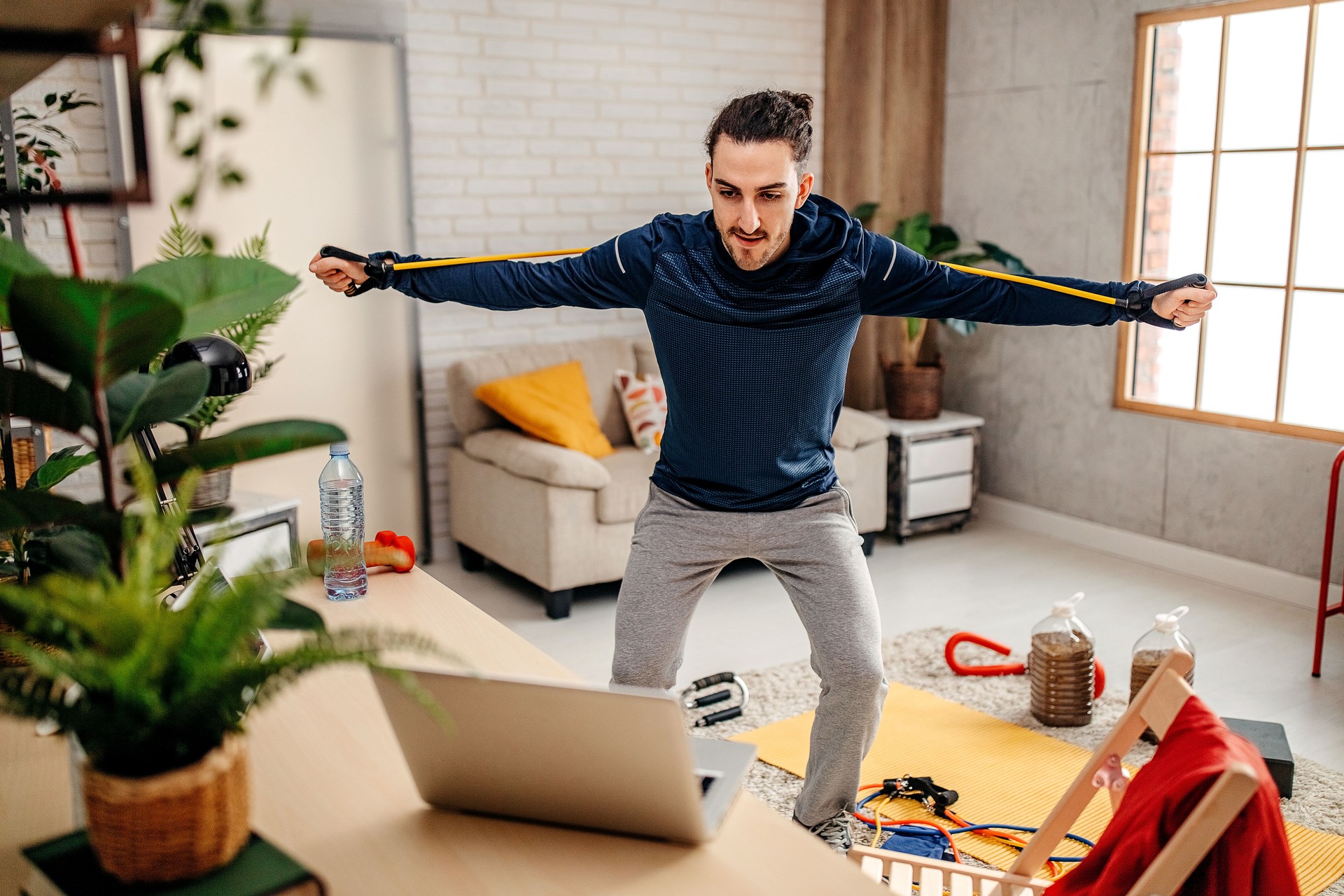 Man doing exercise while watching tutorial on laptop at home